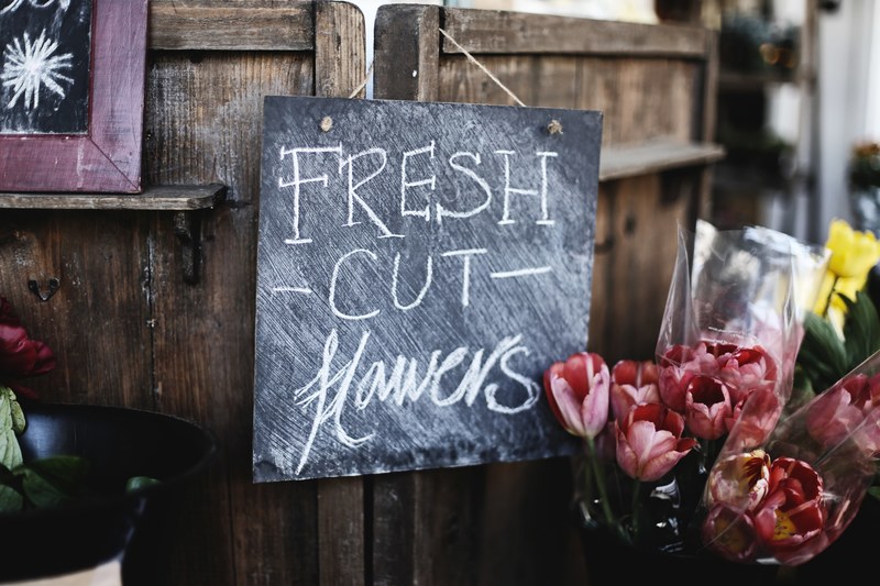 a blackboard reading fresh cut flowers next to a bucket of tulips, fresh flowers at the florists 4k