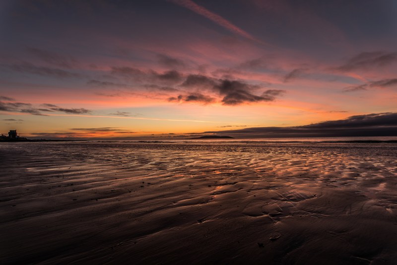 rippled sand with pools of water reflect the moody pink sunset at a beach during dusk, moody beach sunset_ 4k
