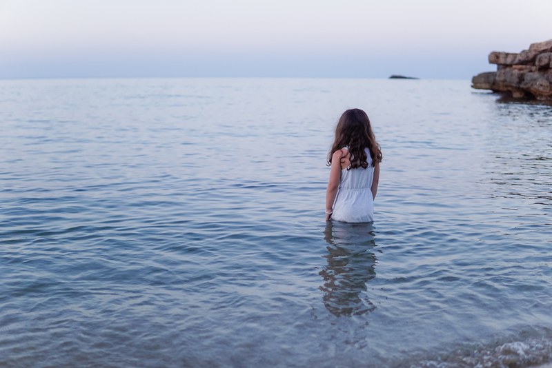 woman in white dress standing by the waist in the ocean in es figueral, woman standing in ocean 4k