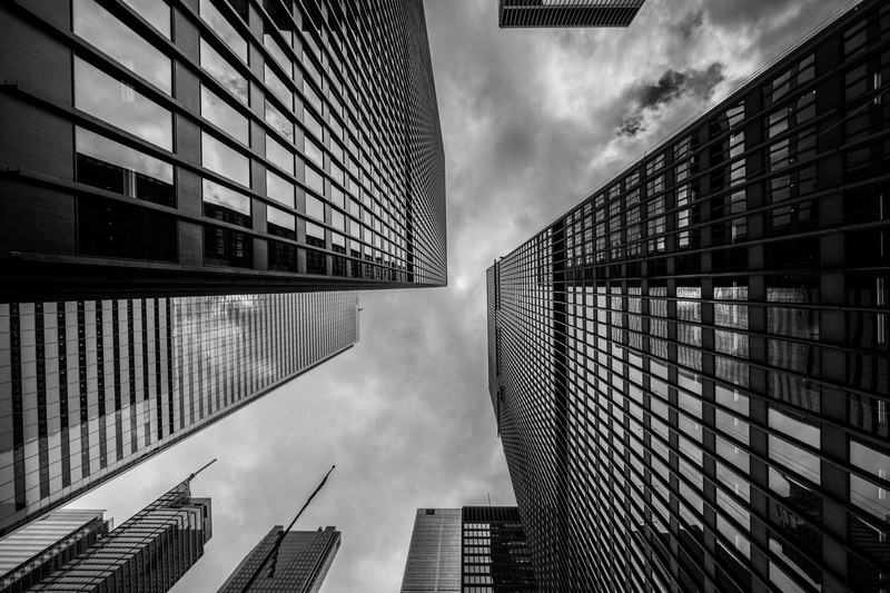 a black and white shot of white clouds above towering high rises in a city, high rises in black and white 4k