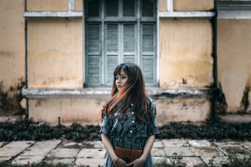 young woman with windswept hair stands near a vintage house, vintage vibes 4k