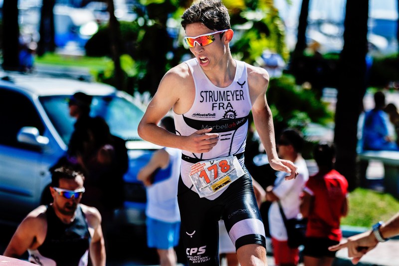 a man wearing orange sunglasses running in a marathon in puerto marina, triatleta 4k