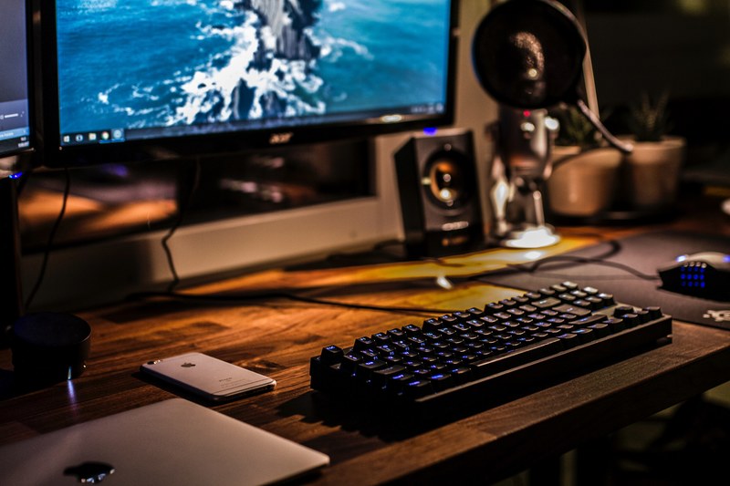 a blurry shot of a computer workspace with a backlit keyboard a laptop and a smartphone, battle amp workstation 4k