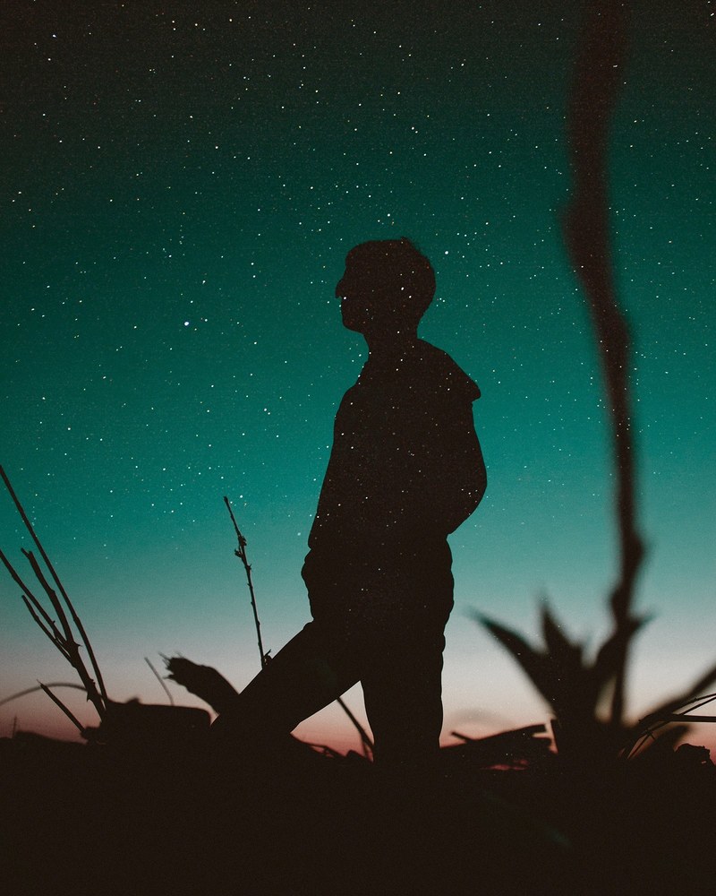 a shot from below of a person in silhouette against a starry teal night sky, untitled guy 4k