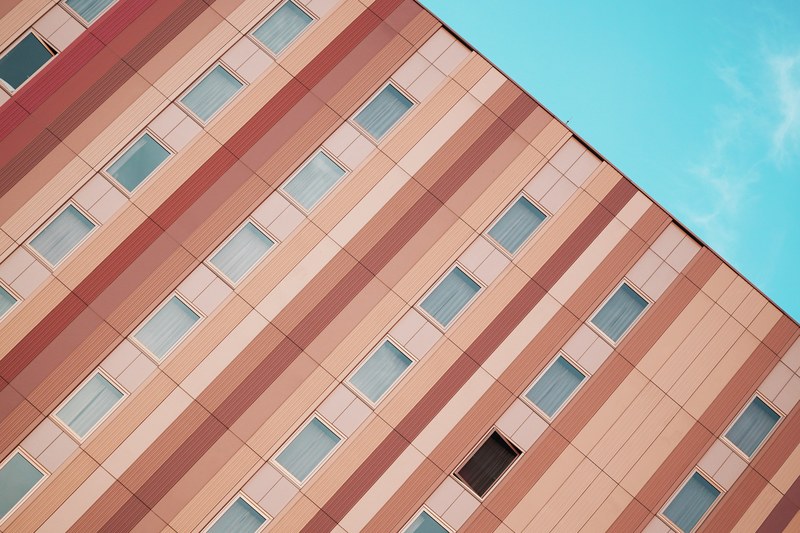an angular shot of a residential building facade painted with pastel colored stripes, pastel stripes on a facade 4k