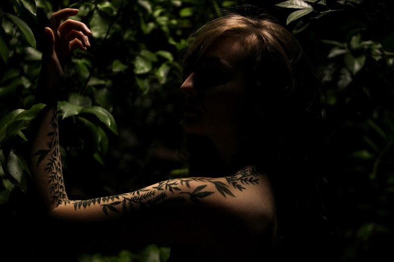 a person stands in shadows at the birmingham botanical gardens showing a leaf print tattoo sleeve, person with tattoo sleeve 4k
