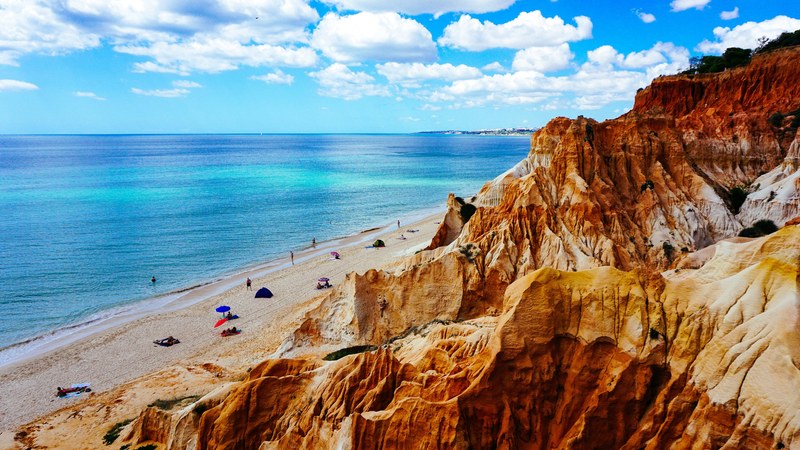 view of rock cliffs by the sand beach coastline on a clear day, rock cliffs on sand coastline 4k
