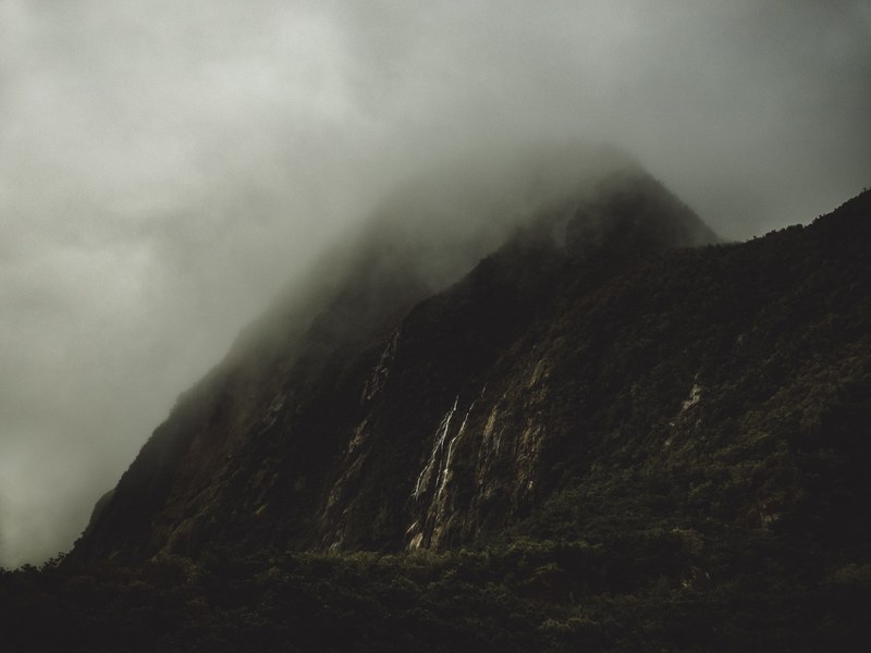 a tall mountain peak with a wooded slope shrouded in dense mist, misty mountains 4k