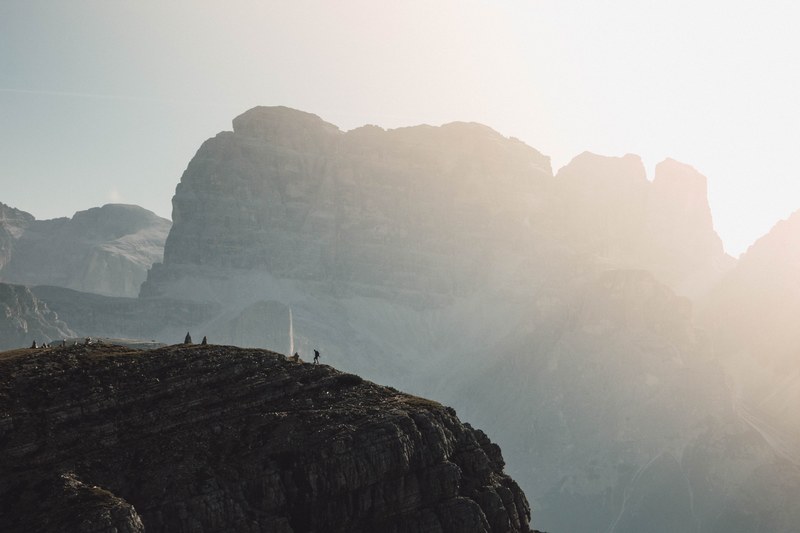 a silhouette of a hiker on a jagged ledge in the dolomites, hiking in the tall dolomites 4k