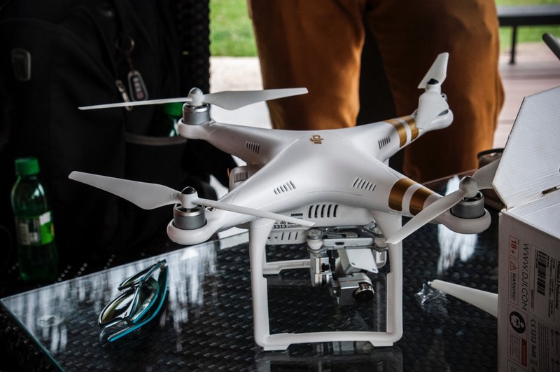 a white dji phantom 3 drone on a glass table next to a pair of sunglasses, quadcopter on a table 4k