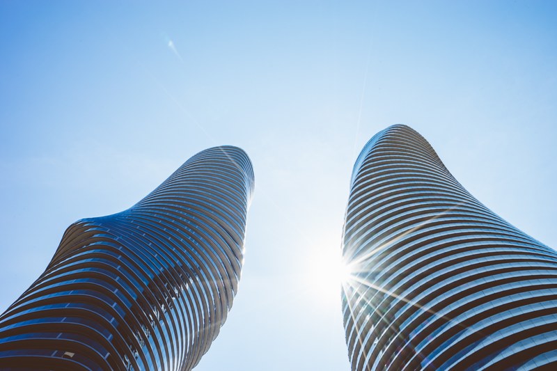 bright shining sun behind a twin tower skyscraper, twin twisting towers 4k