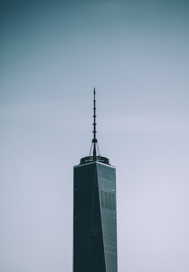 a skyscraper with a tall spire against a pale blue sky, skyscraper with a spire 4k