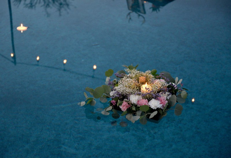 a box with a burning candle surrounded with various flowers and leaves floating on the surface of water, floating flower box 4k
