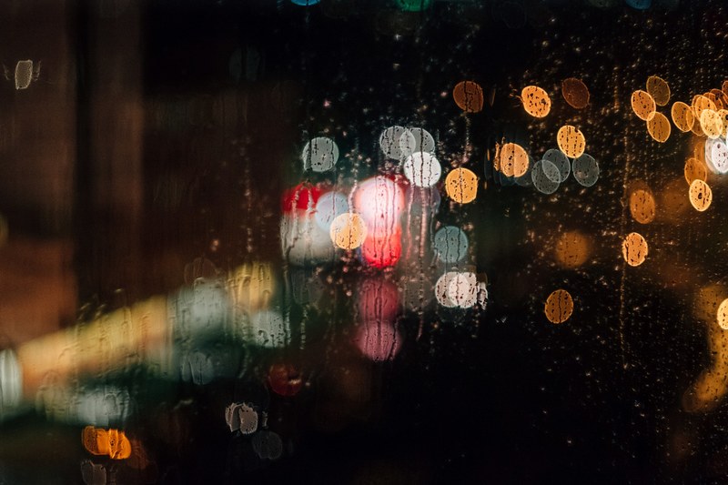a rain streaked window with a bokeh effect, lights behind a rainy window 4k