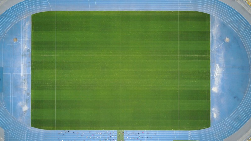 drone aerial view of a blue tartan track and field track with the green grass pitch in the middle at kiev gorod kiev ukraina, drone view of green field and tartan field 4k