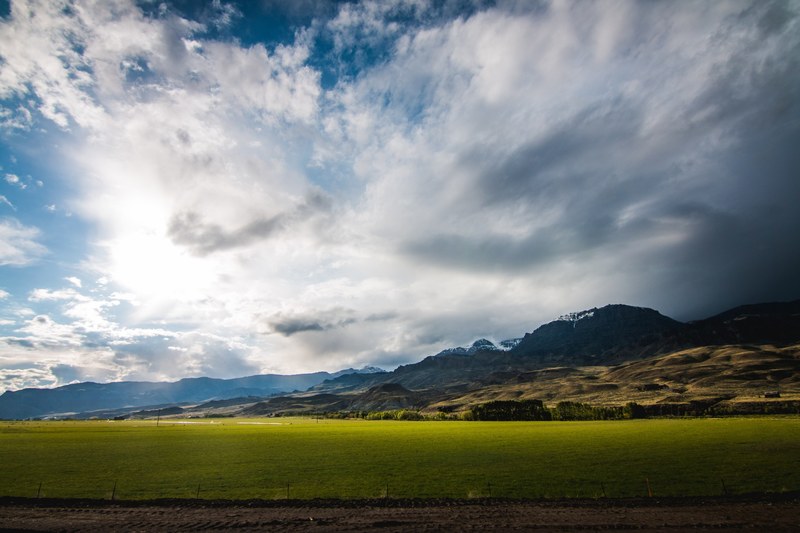 tranquil pastures in a rural valley below snowy mountains on the horizon, empty pasture at the mountains foot 4k