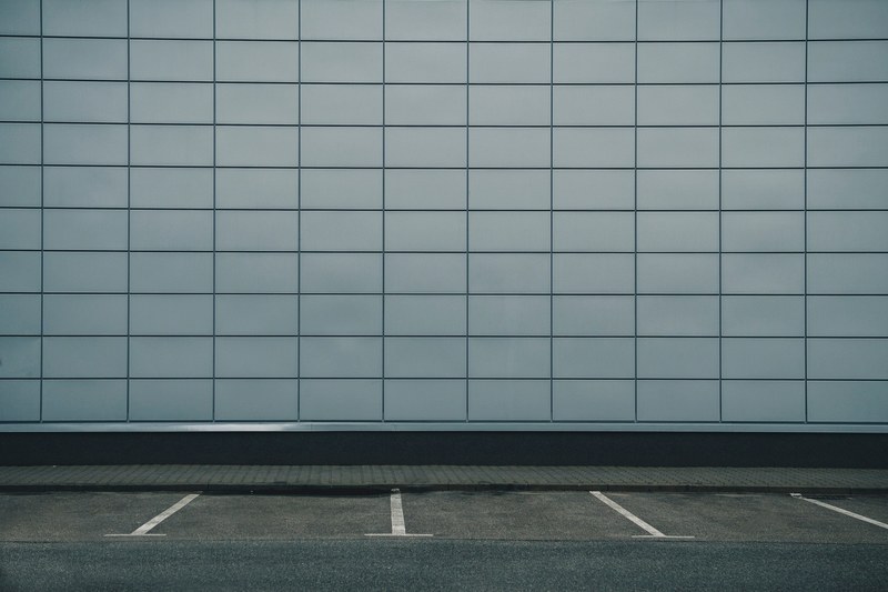 an empty parking lot against a grey tiled wall of a building, _greys 4k