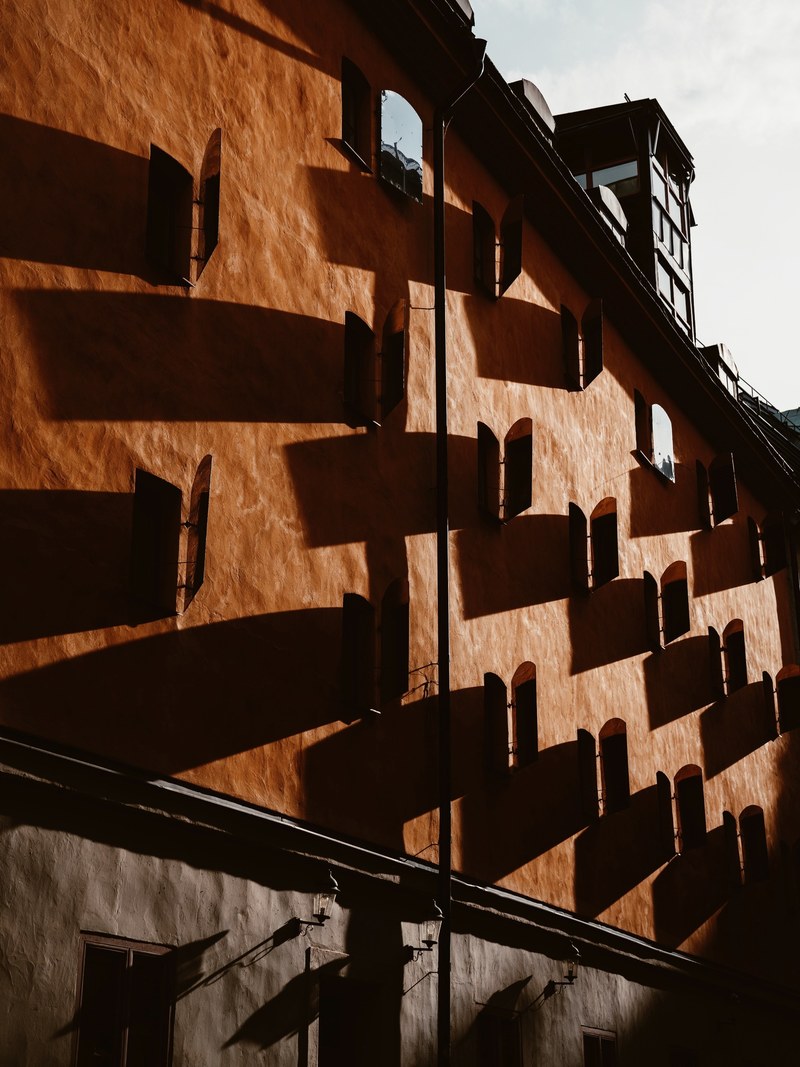 a building with rows of mirrors on its wall as seen in old town, _shadows in old town 4k