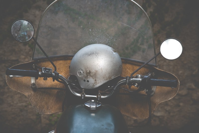 a scratched metal motorcycle helmet sitting on motorcycle handles beside circular mirrors, motorcycle and helmet 4k