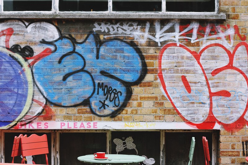 grunge graffiti on brick wall behind colorful tables and chairs in shoreditch, coffee time 4k