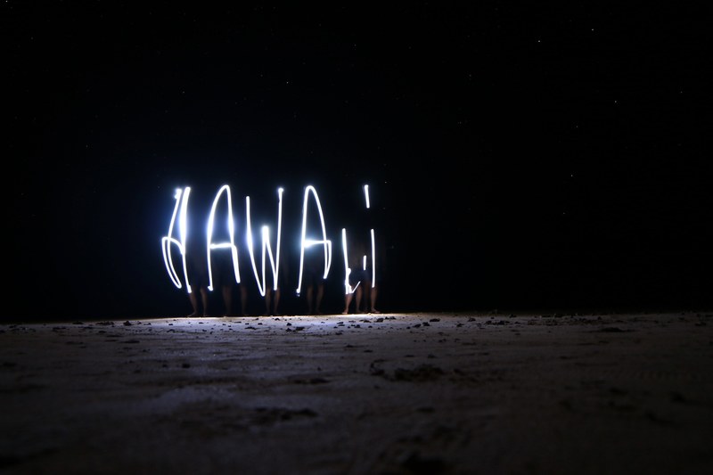 a night time light painting that spells out hawaii taken on anini beach, on the beach in hawaii 4k