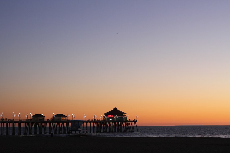the sun setting behind the twinkling lights of the huntington beach pier california, winter sunsets 4k