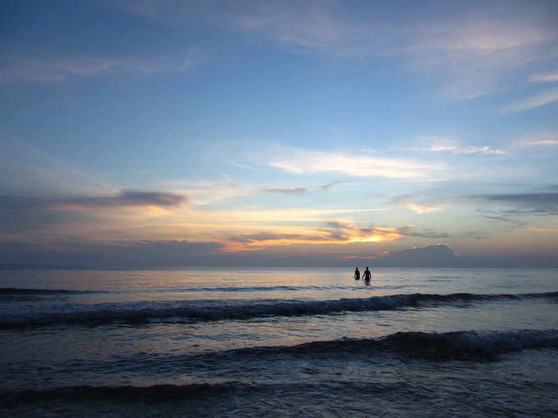 silhouettes of two people wading through the sea at twilight, evening swim in the sea 4k
