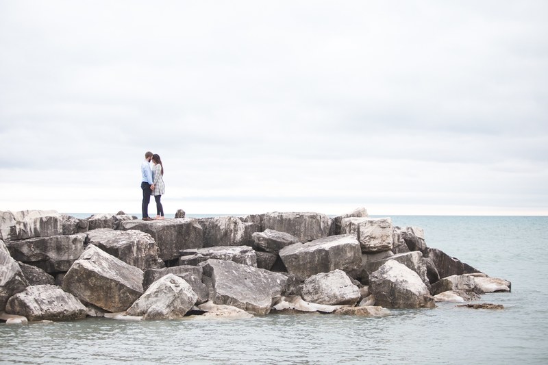 standing on a stone jetty on the ocean a couple shares a tender moment, on the jetty 4k