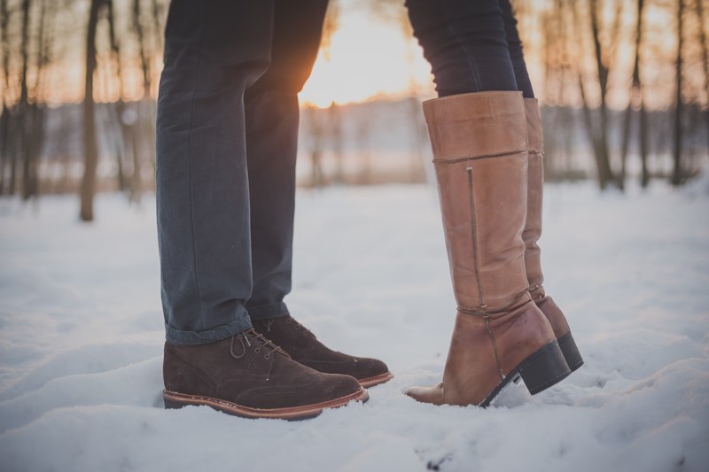 on a snowy day a woman in boots rises on tip toe to kiss a man, boots in snow 4k