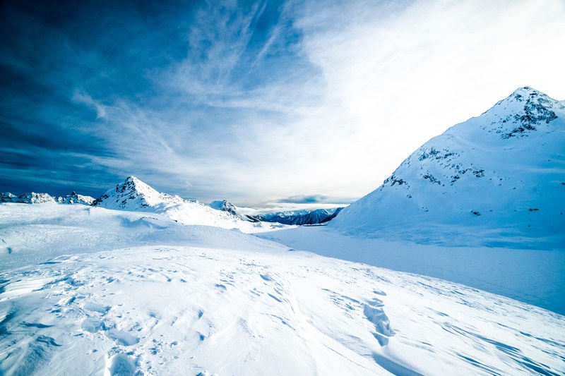 a frozen landscape with mountains coated with a thick layer of snow, frozen mountainous landscape 4k
