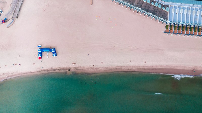 a drone shot of an empty sandy beach with a small blue pavilion, freedom 4k