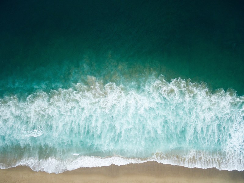 drone aerial view of the waves washing on the redondo sand beach, high as a kite 4k