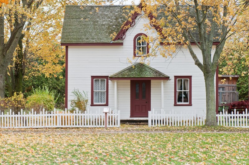 a small white house surrounded by trees in the autumn, small house on an autumns day 4k