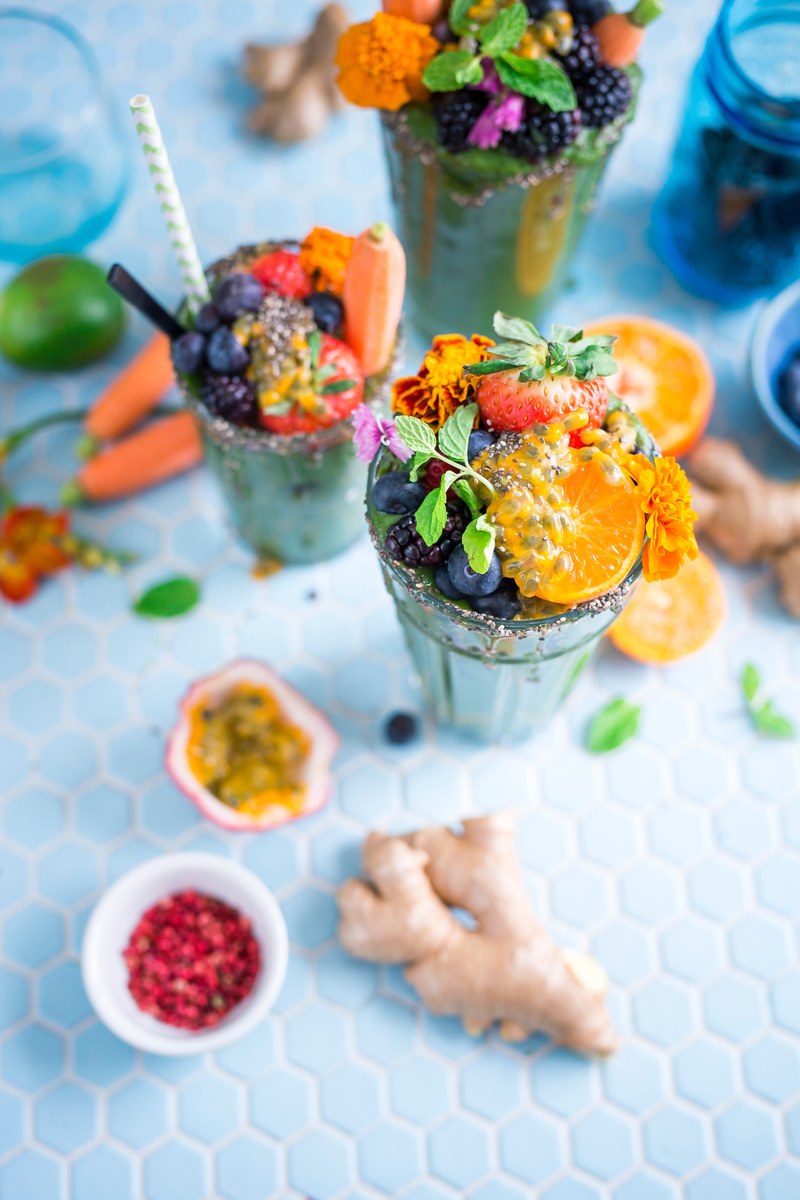 fruit smoothies in glasses topped with pieces of fruit and marigold flowers, everything but the kitchen sink 4k