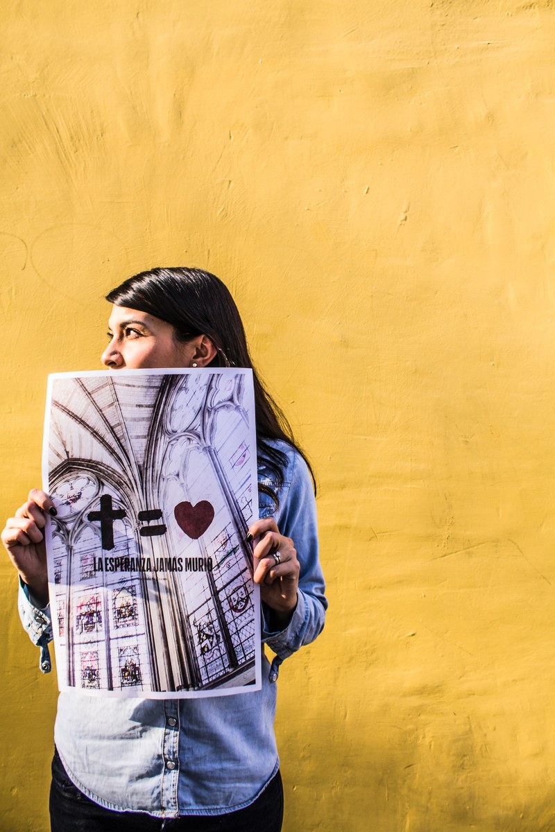 an indian person holding up a poster that says a cross equals love, _love 4k