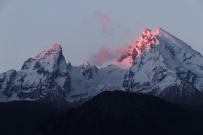 a tall mountain summit illuminated by the setting sun on the other side of the ridge, setting sun behind the mountain 4k