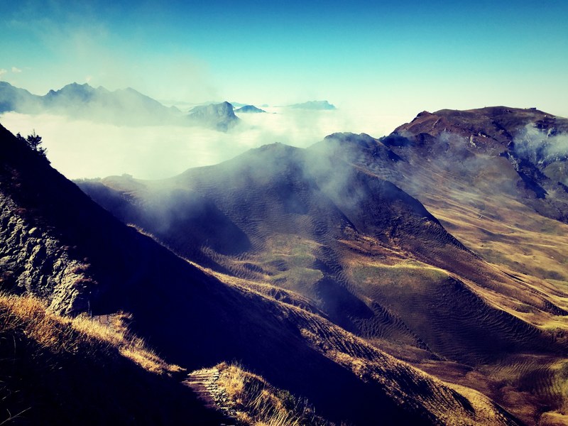 waving mountains covered in light mist under a blue sky, light mist over mountains in fronalpstock 4k