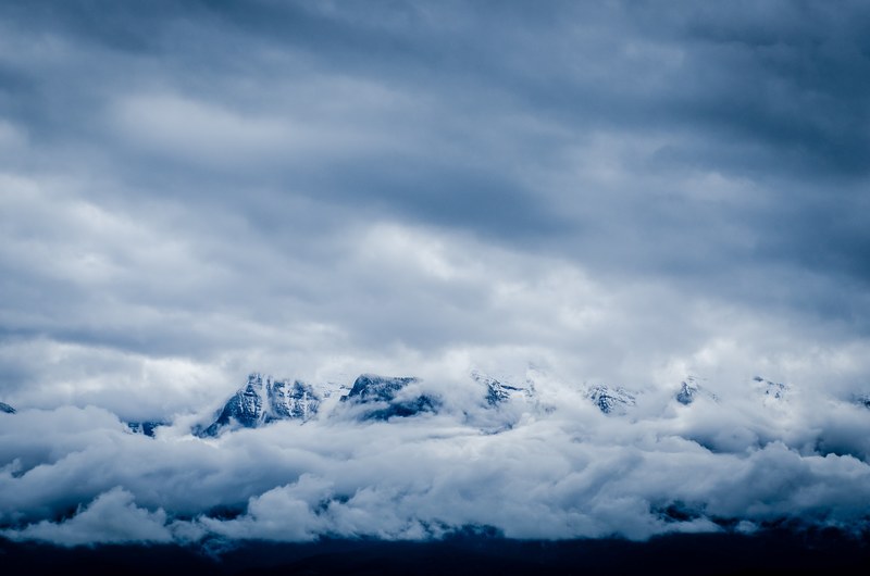thick clouds swirling around icy snowy mountains, snowy mountains and cloudy sky 4k
