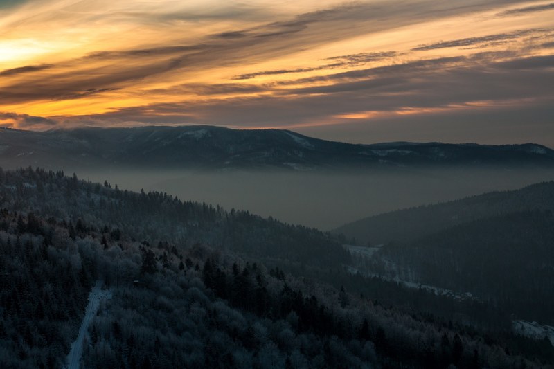 sun is rising behind clouds while the mountains are still laying in fog, sun peaks through misty mountains 4k