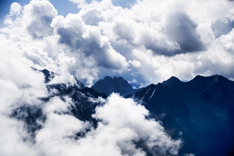clouds partly obscuring the view on a tall mountain range, clouds descending on the mountains 4k