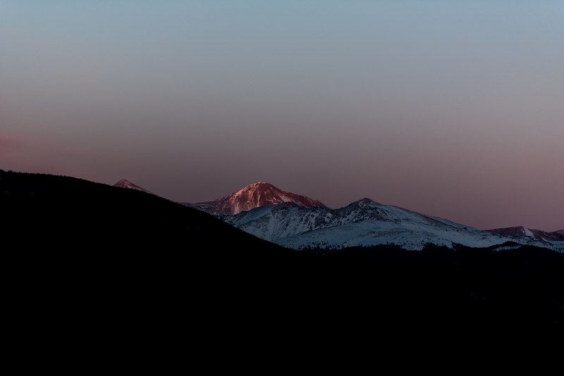 a dim shot of distant mountain peaks under the evening sky, pale snowy mountains 4k