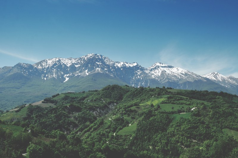green wooded hills near tall snow topped mountains, green hills near mountains 4k