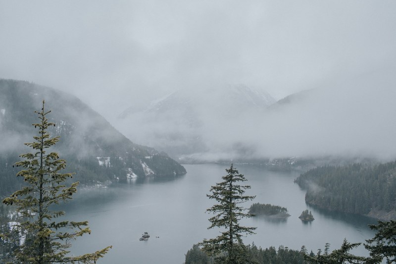 fog rolls in over calm waters on a misty morning in diablo lake, mist and mountains 4k