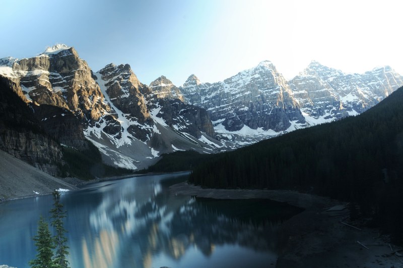 the moraine lake is showing a reflection of the snowcapped mountains surrounding it, calm waters between mountains 4k