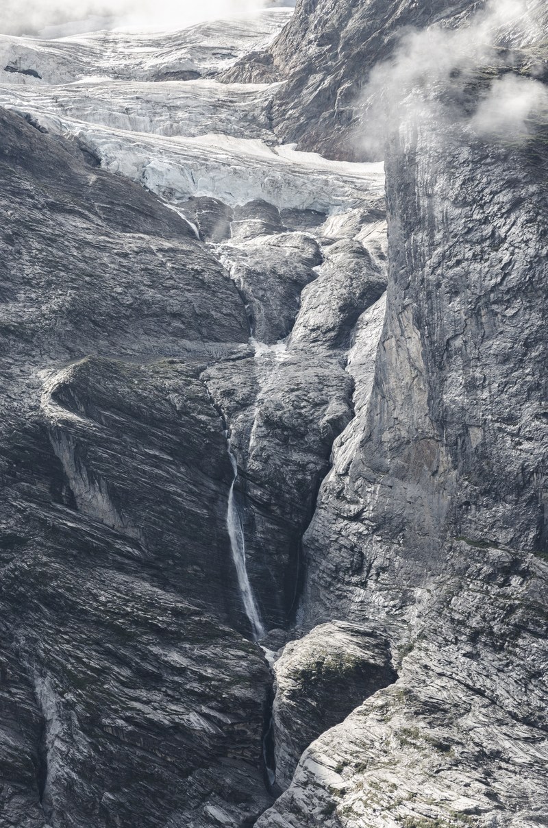 cliff face with a waterfall cascading down it and clouds at the top, cliff face waterfall 4k
