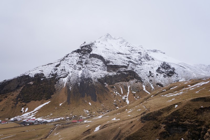 buildings at the foot of a tall snowy mountain, iceland 4k