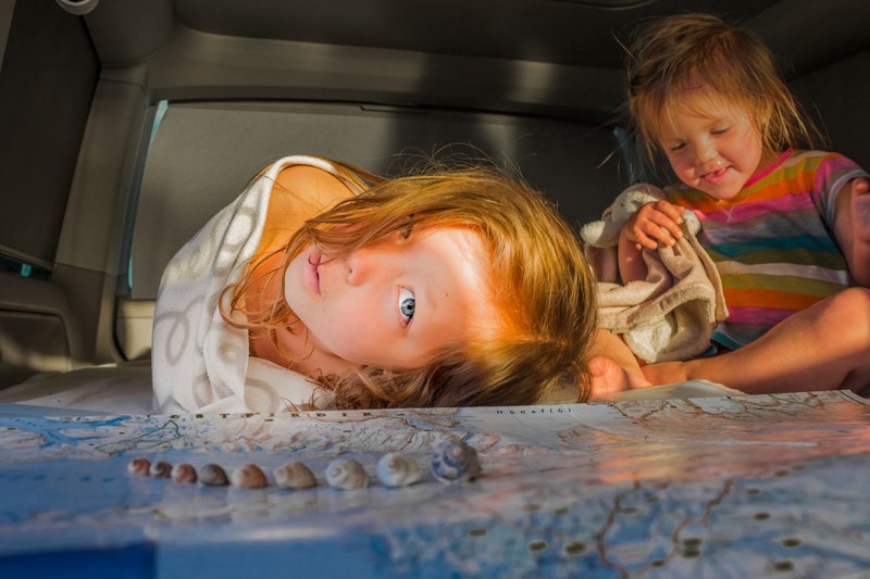 two small children playing over a map in a car, children playing by the map 4k