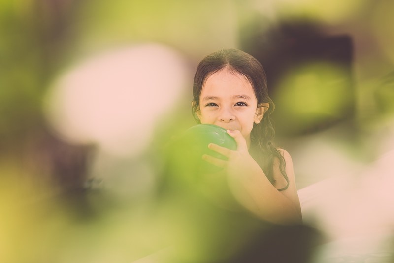 a child holds a balloon in front of her face against a fuzzy background in aracaju, fada 4k