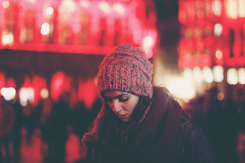 a woman in a knit cap looks down against red lights at the grand palace, brussels lights 4k