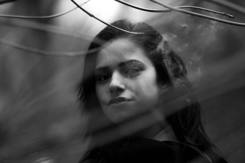 black and white shot of attractive dark haired woman with branches, at the center of the focus 4k